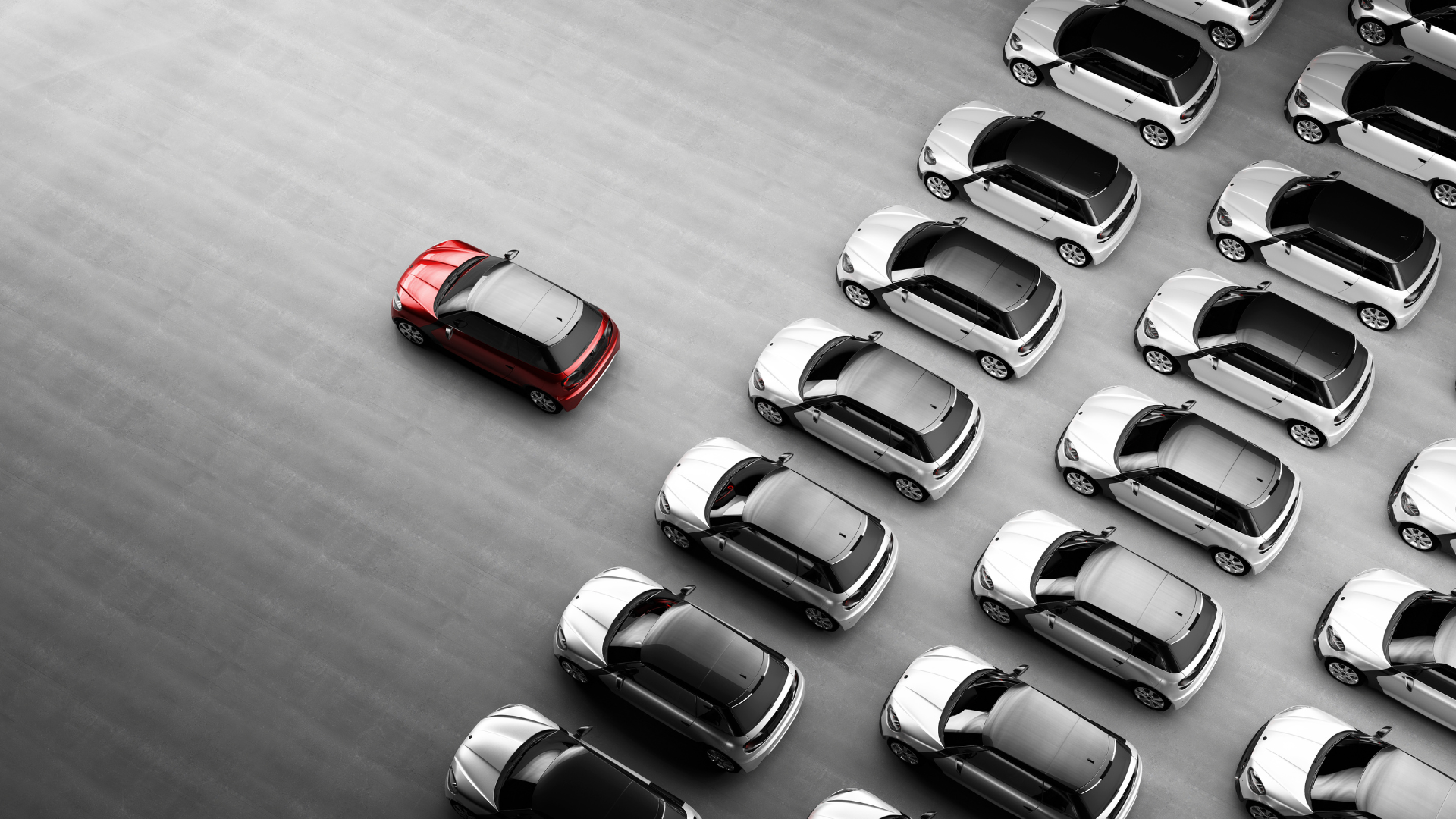 Vista aérea de uma frota de veículos brancos estacionados, com um único veículo vermelho em destaque